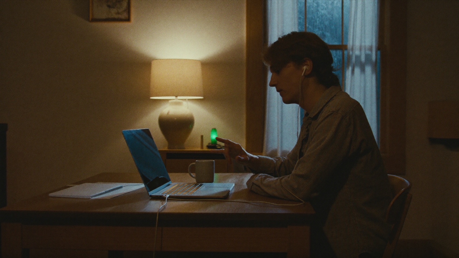 A warm kitchen late in the evening, somebody at the table talking casually toward a laptop pushed to one side.