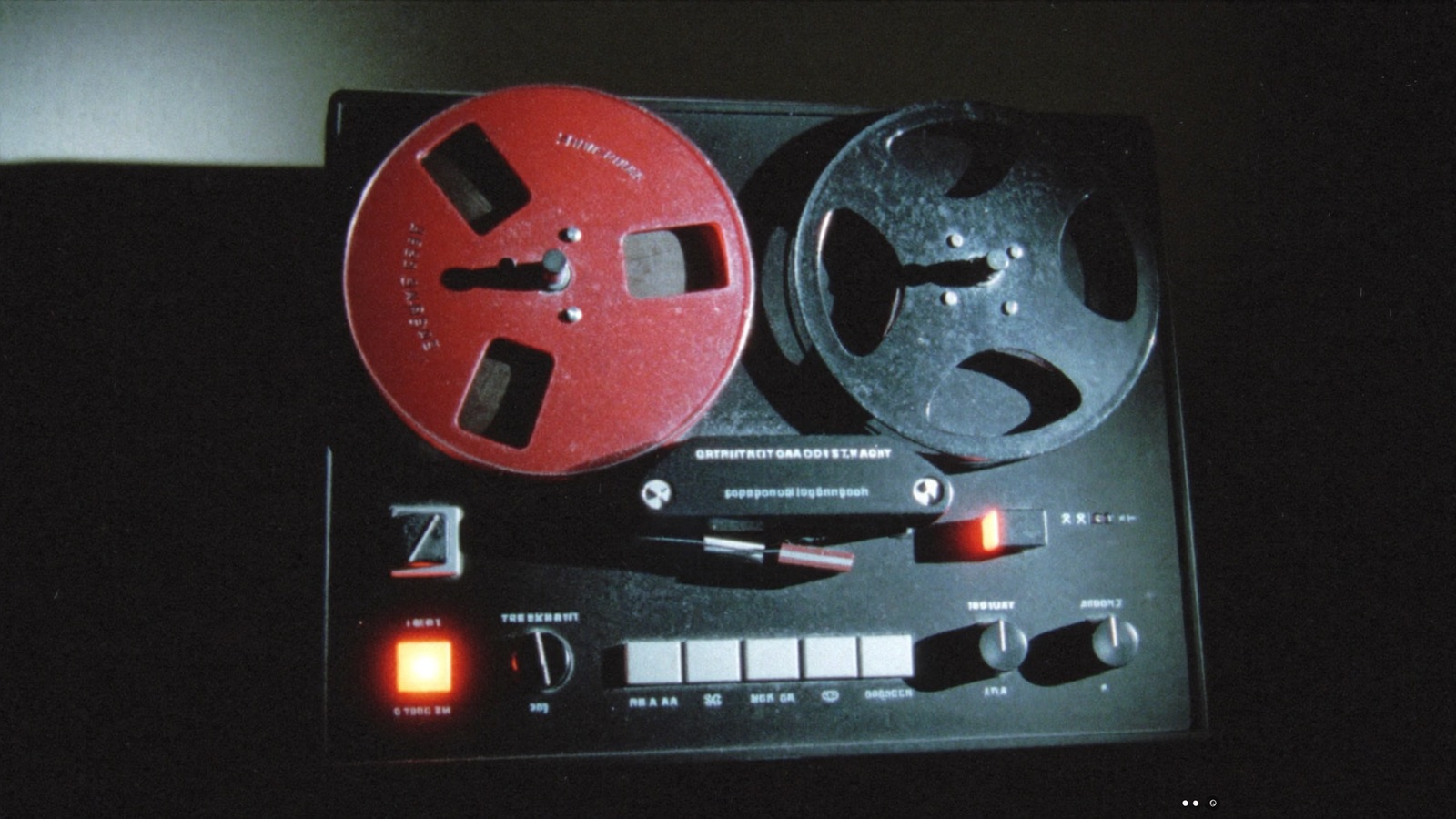 A reel-to-reel tape recorder switched off in a dark room, its record light unlit.